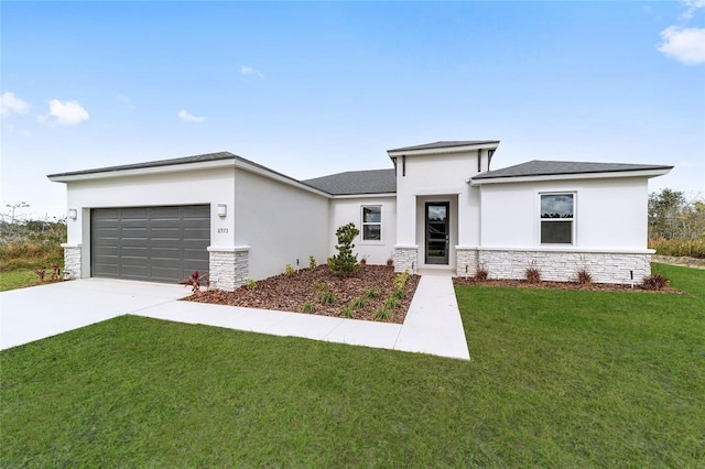 prairie-style home with a front yard, an attached garage, stone siding, and driveway