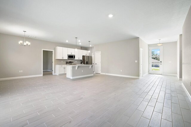 unfurnished living room with light wood-type flooring and an inviting chandelier