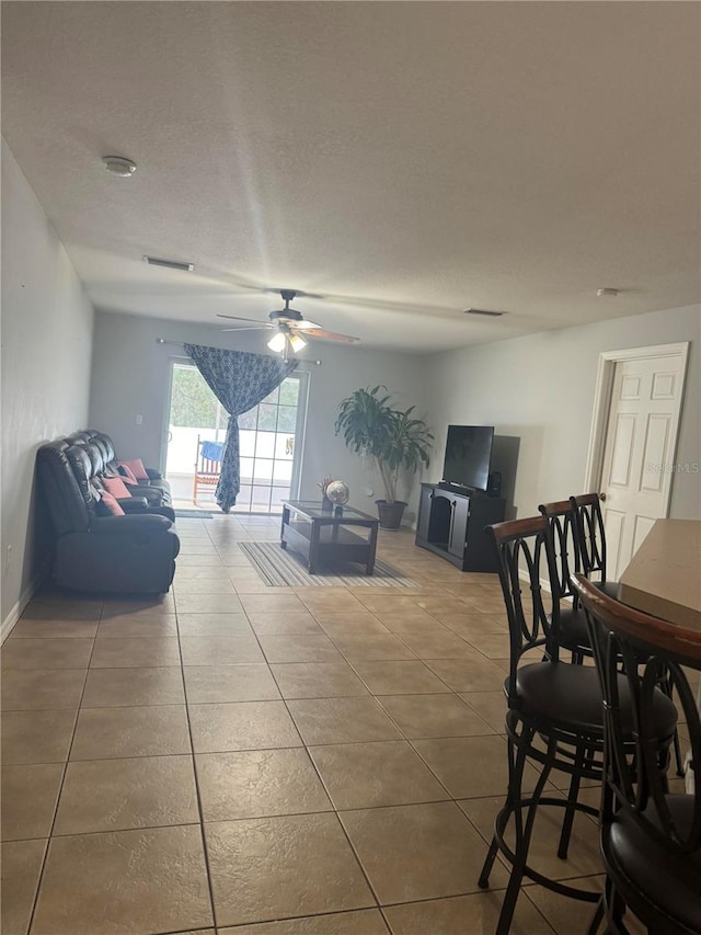 living room featuring a textured ceiling, ceiling fan, and tile patterned floors