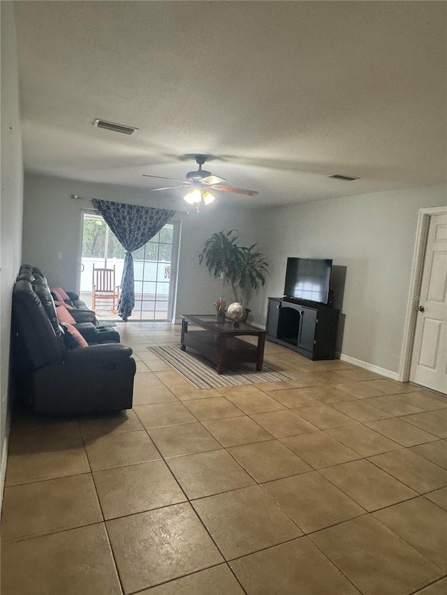 living room with ceiling fan, light tile patterned floors, and a textured ceiling