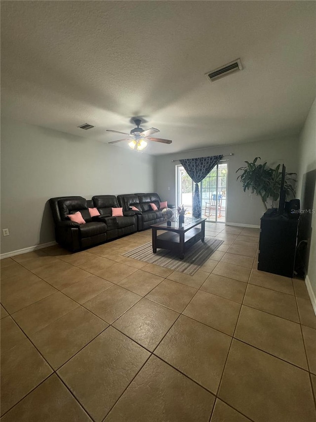 living room with a textured ceiling, ceiling fan, and tile patterned floors