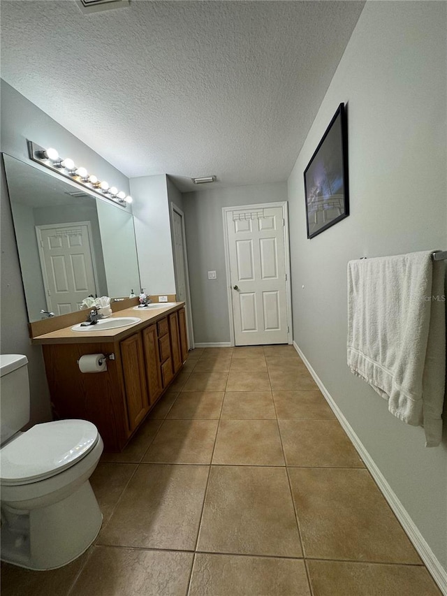 bathroom featuring tile patterned flooring, toilet, a textured ceiling, and vanity