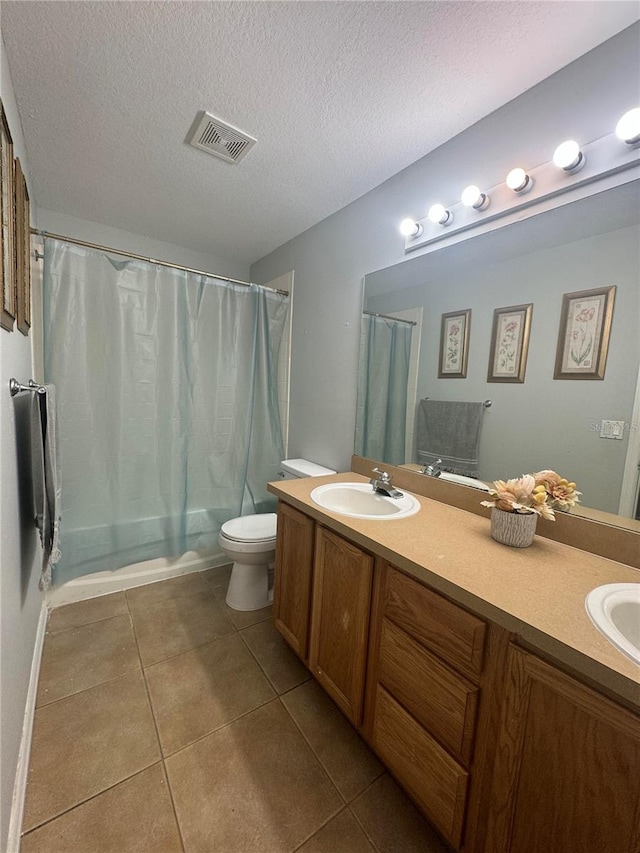 bathroom featuring toilet, tile patterned flooring, vanity, a textured ceiling, and curtained shower