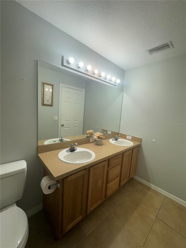 bathroom with vanity, toilet, tile patterned floors, and a textured ceiling