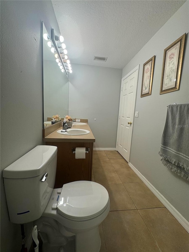 bathroom featuring tile patterned flooring, toilet, a textured ceiling, and vanity