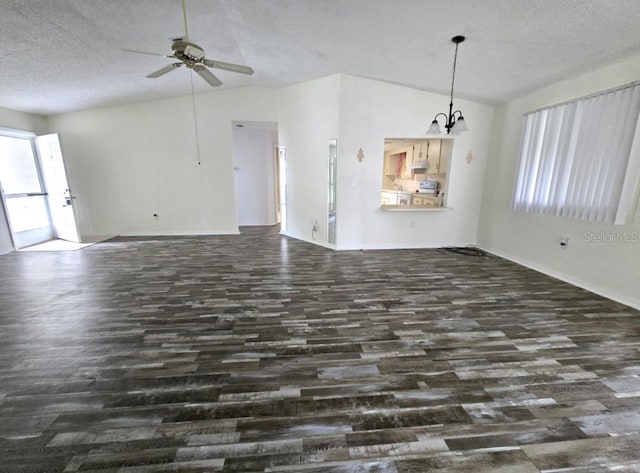 unfurnished living room featuring dark wood-style flooring, a textured ceiling, vaulted ceiling, and ceiling fan with notable chandelier