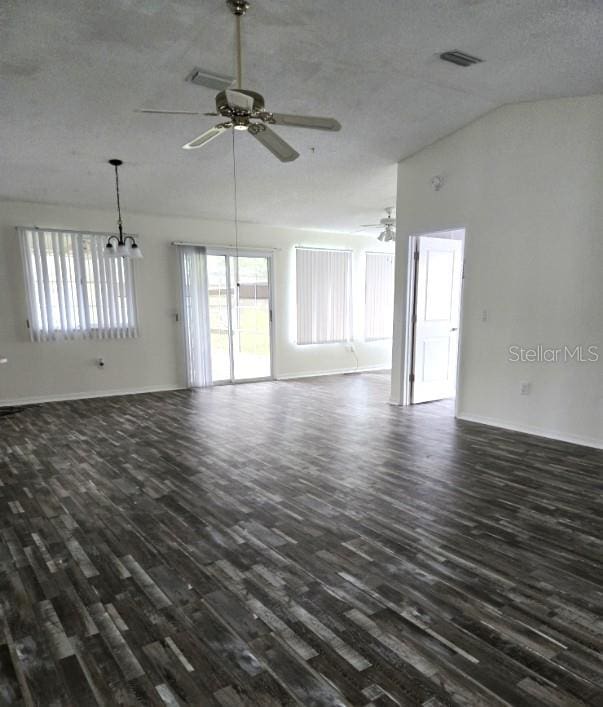 unfurnished living room featuring vaulted ceiling, a textured ceiling, ceiling fan with notable chandelier, visible vents, and dark wood-style flooring