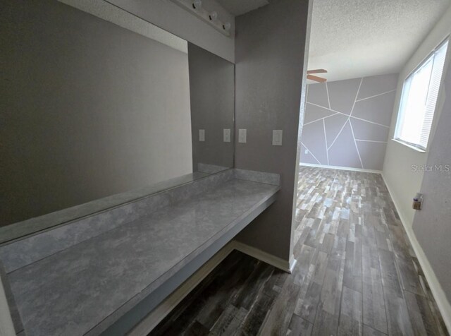 interior space featuring baseboards, a textured ceiling, wood finished floors, and ceiling fan