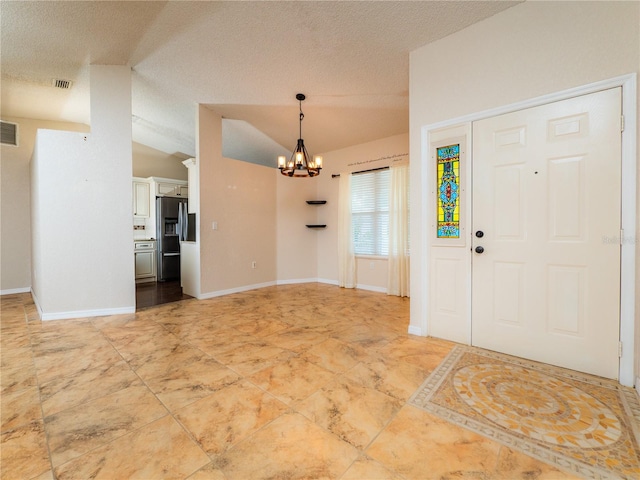 foyer entrance with a chandelier, a textured ceiling, and vaulted ceiling