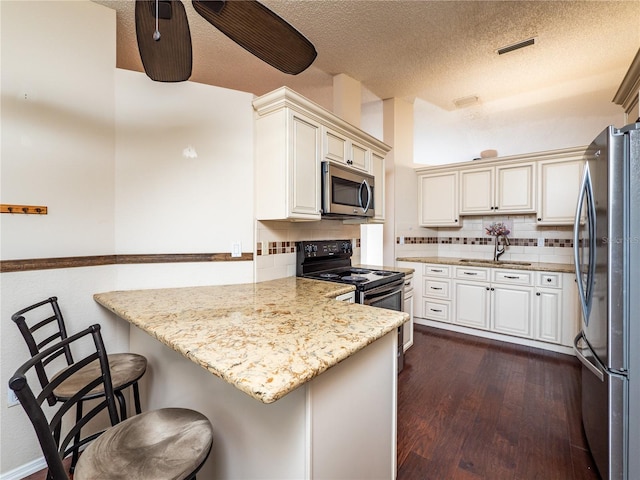 kitchen with a kitchen breakfast bar, kitchen peninsula, light stone counters, and stainless steel appliances