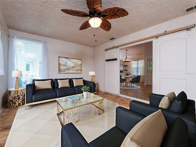 living room featuring a barn door and ceiling fan with notable chandelier