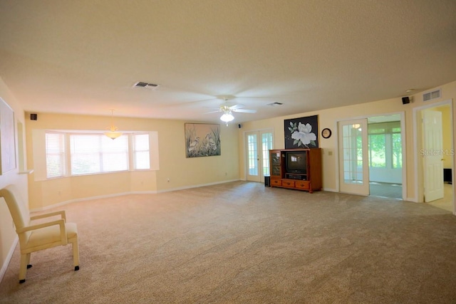 unfurnished living room featuring a textured ceiling, carpet, and ceiling fan