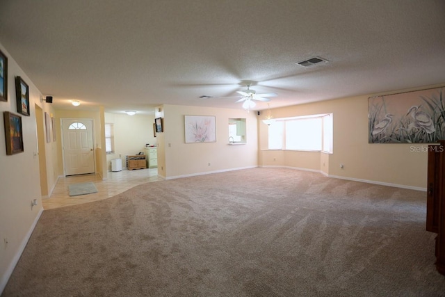 unfurnished living room with ceiling fan, light carpet, and a textured ceiling