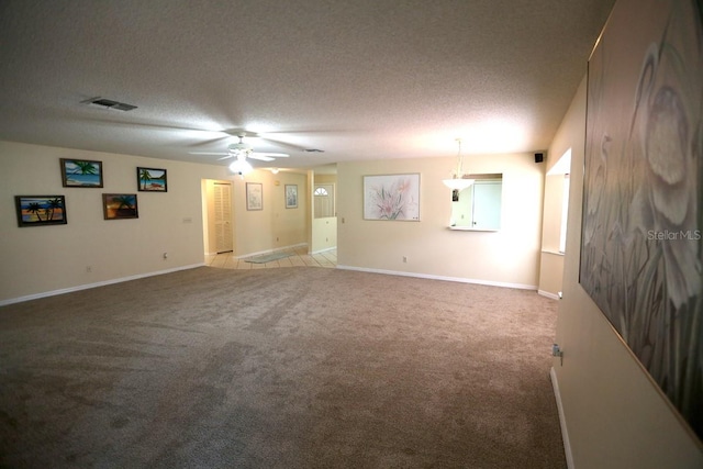 carpeted empty room featuring ceiling fan and a textured ceiling