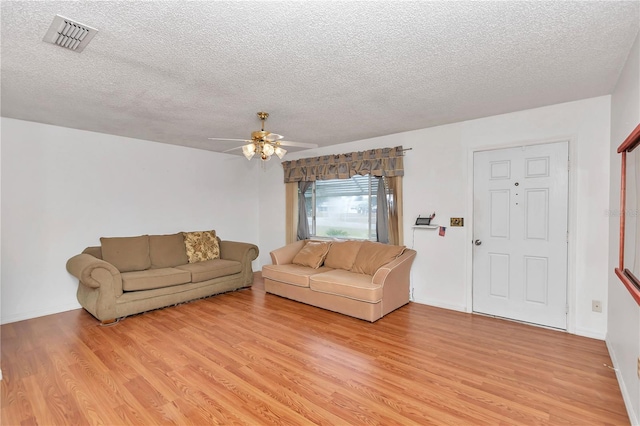 living room featuring ceiling fan, a textured ceiling, and light hardwood / wood-style floors