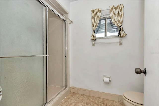 bathroom with a shower with door and toilet