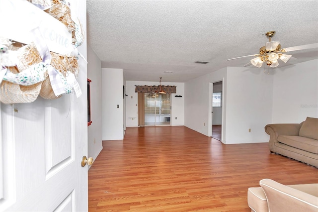 living room featuring ceiling fan, light hardwood / wood-style floors, and a textured ceiling