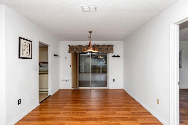 unfurnished dining area featuring hardwood / wood-style floors and a textured ceiling