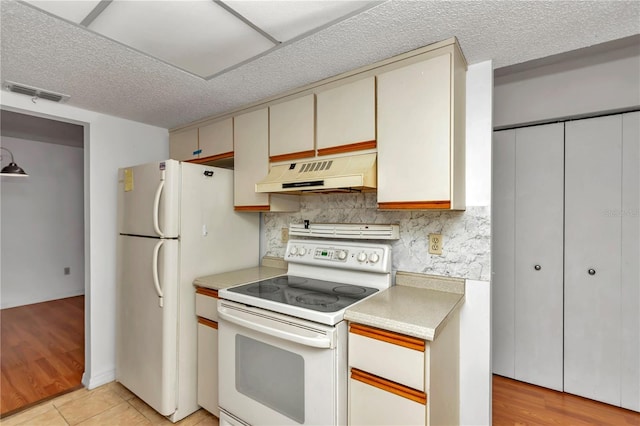 kitchen featuring white appliances, decorative backsplash, and light tile patterned flooring