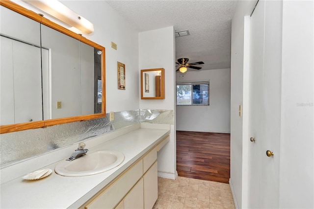 bathroom with vanity, ceiling fan, and a textured ceiling