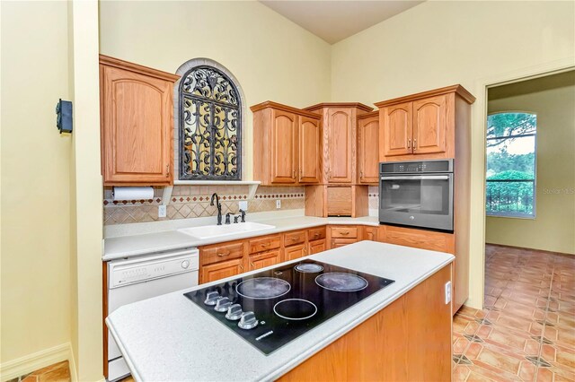 kitchen with backsplash, dishwasher, sink, black electric cooktop, and stainless steel oven