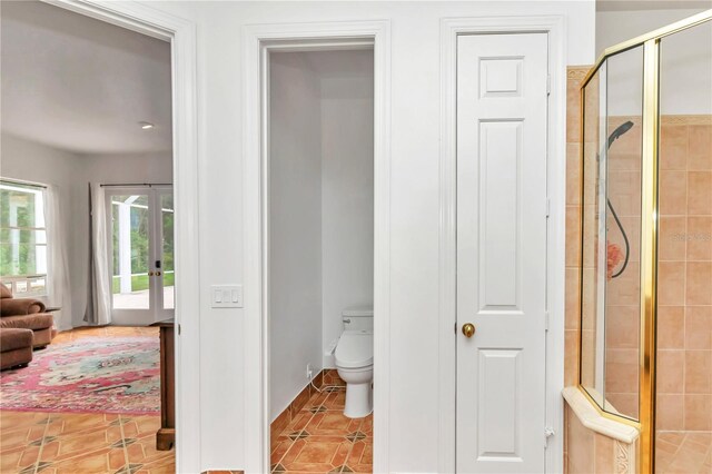 bathroom with toilet, a shower with shower door, and tile patterned flooring