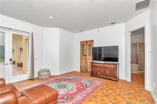 tiled living room with french doors and a textured ceiling