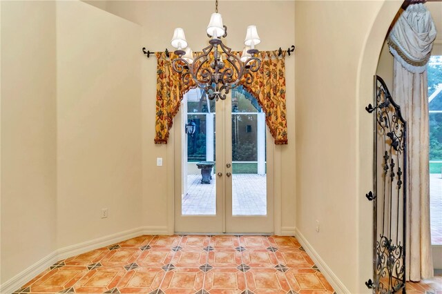 entryway featuring french doors, a wealth of natural light, a chandelier, and tile patterned floors