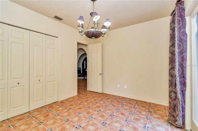 unfurnished bedroom featuring a closet and an inviting chandelier