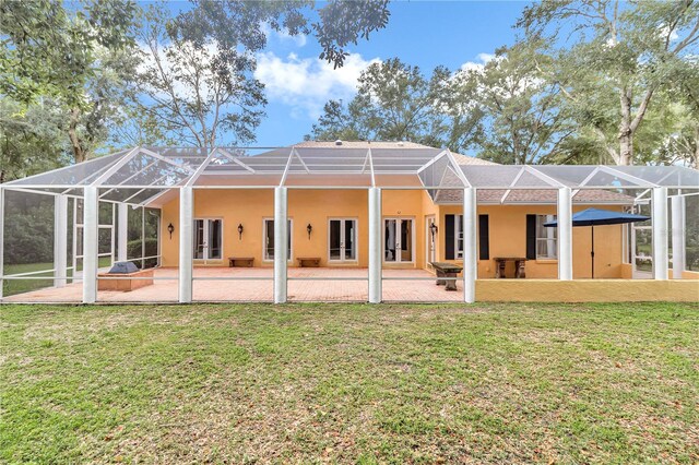 back of house featuring a lawn, a patio area, and glass enclosure