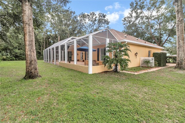 rear view of house with glass enclosure and a yard