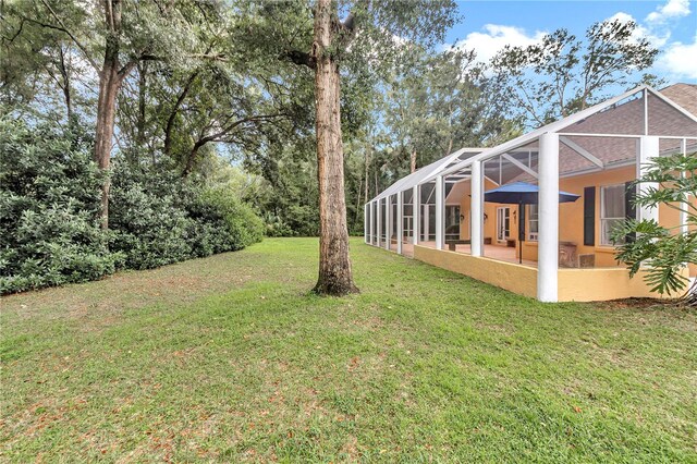 view of yard featuring glass enclosure and a patio area