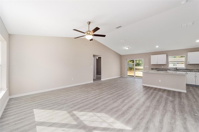 unfurnished living room with ceiling fan, light wood-type flooring, and vaulted ceiling