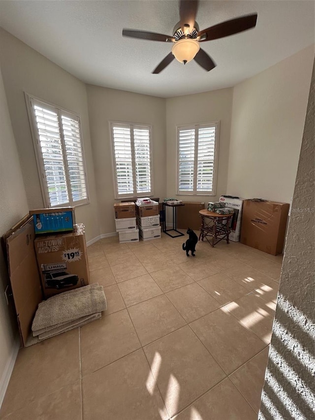 misc room with a textured ceiling, light tile patterned floors, and ceiling fan