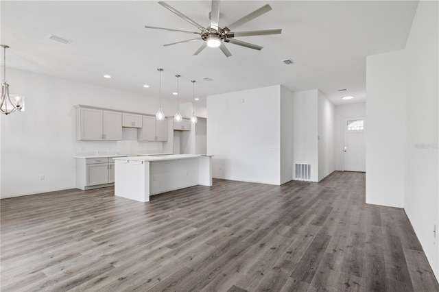 kitchen featuring ceiling fan with notable chandelier, a center island, dark hardwood / wood-style floors, and hanging light fixtures