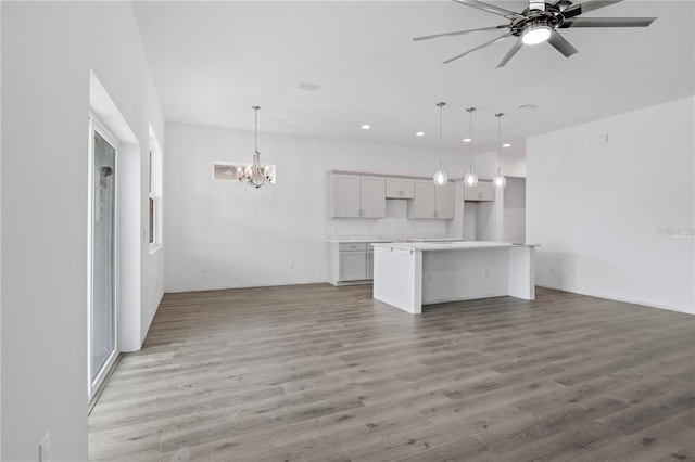 kitchen featuring light wood-type flooring, ceiling fan with notable chandelier, a kitchen island, and hanging light fixtures