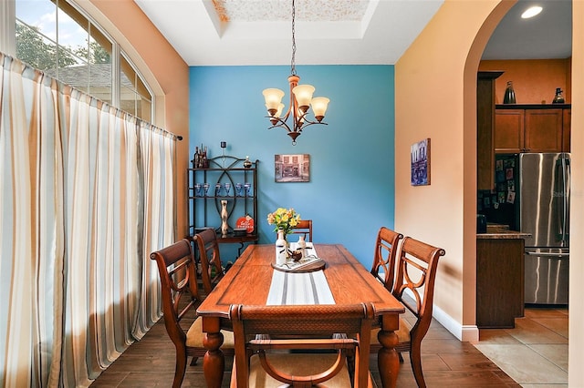 dining space with a raised ceiling, a chandelier, and dark hardwood / wood-style floors