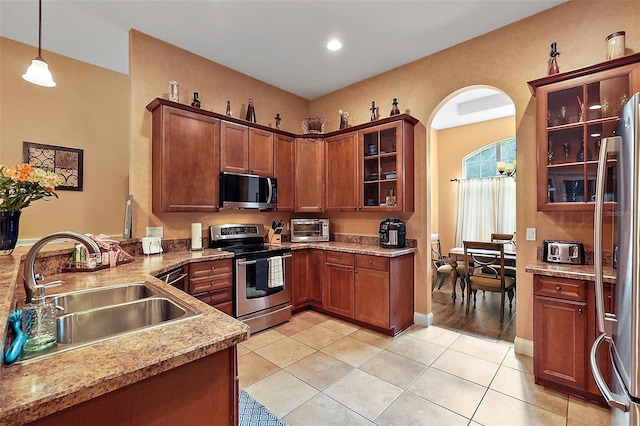 kitchen featuring decorative light fixtures, light stone countertops, light tile patterned floors, stainless steel appliances, and sink