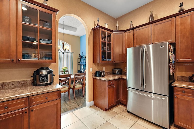 kitchen with light hardwood / wood-style flooring, light stone counters, stainless steel fridge, and an inviting chandelier