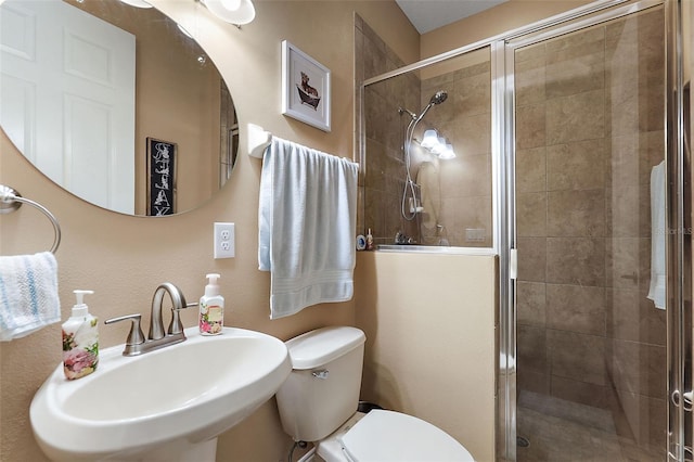 bathroom with a shower with door, toilet, and sink