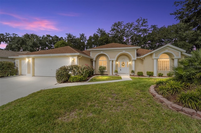 mediterranean / spanish house featuring a garage and a lawn