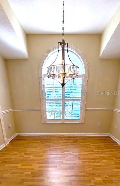 unfurnished dining area with hardwood / wood-style flooring and a chandelier