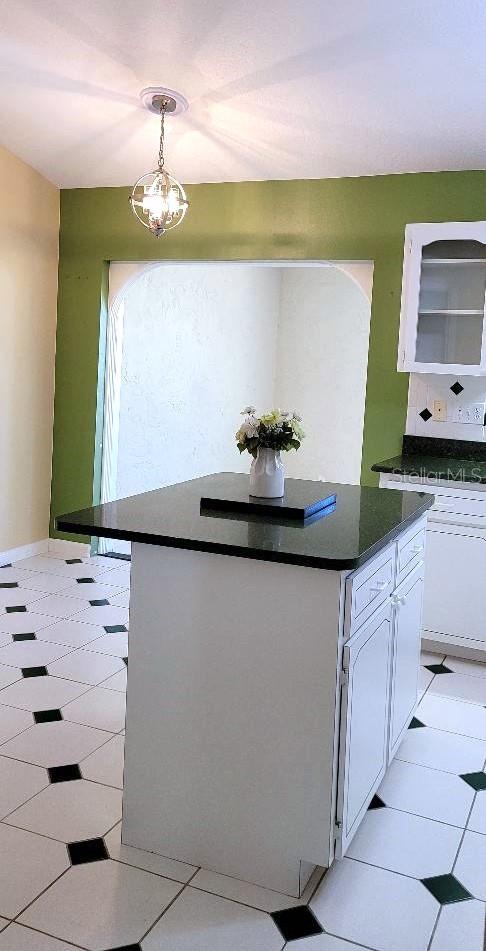 kitchen featuring a chandelier, pendant lighting, white cabinetry, and a kitchen island