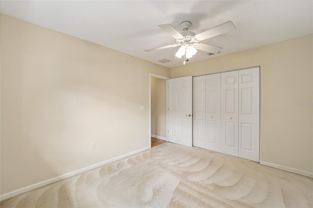 unfurnished bedroom featuring ceiling fan, light colored carpet, and a closet