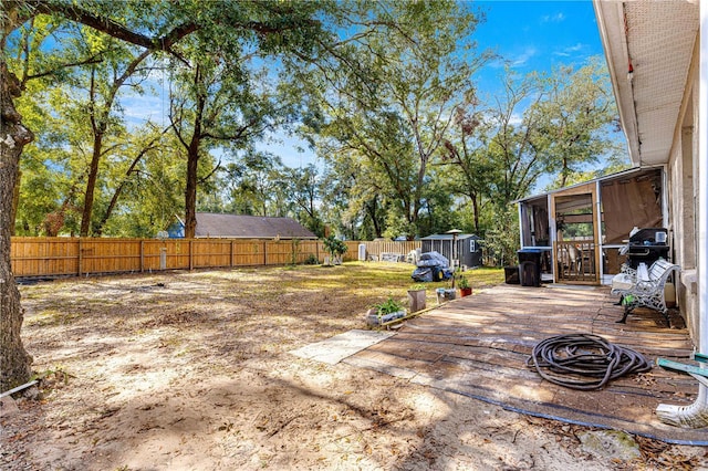 view of yard featuring a shed, a deck, and a sunroom