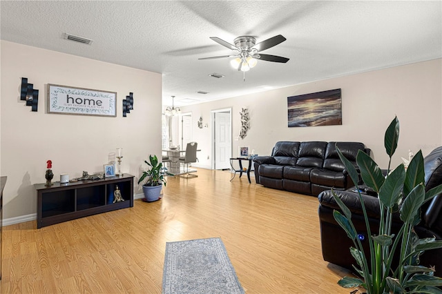 living room featuring wood-type flooring, ceiling fan, and a textured ceiling