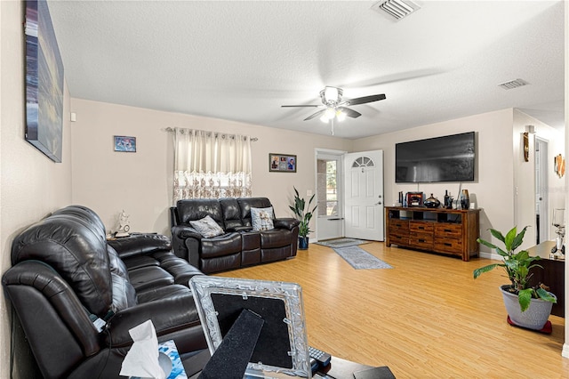 living room featuring wood-type flooring, ceiling fan, and a textured ceiling