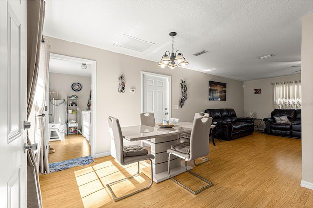 dining room featuring a notable chandelier, light hardwood / wood-style flooring, and a textured ceiling