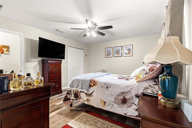 bedroom with a textured ceiling, a closet, ceiling fan, and light wood-type flooring