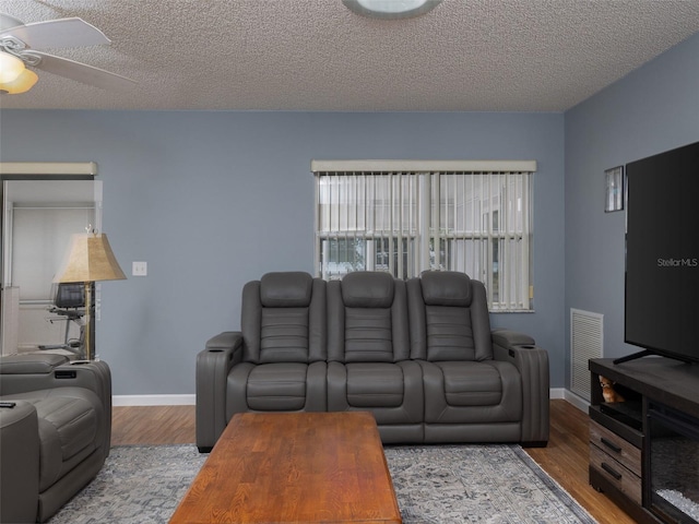 living room with ceiling fan, a textured ceiling, and light hardwood / wood-style flooring